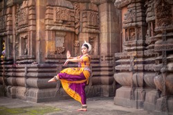 Indian classical odissi dancer at Brahmesvara Temple with sculptures in bhubaneswar, odisha, India
