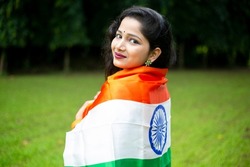 Indian young girl waving indian tricolour flag outdoor park, conceptual image for republic day or independence day greeting.Celebrating Independence Day of India Azadi Ka Amrit Mahotsav. Indian Cultur