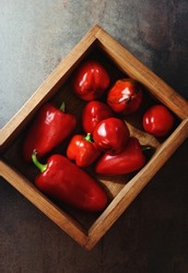 Red bell peppers in wooden box on dark background. Close up of fresh vegetables, a source of vitamin A, C and folate.