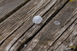 Small balls of hail, ice and hailstones from the sky on an old wooden table on a sunny day. Summer.