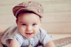 Adorable happy baby boy in a bright room. The baby in the hat smiling looking at camera. Retro style