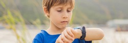 Boy uses kids smart watch outdoor against the background of the garden BANNER, LONG FORMAT