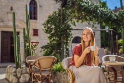 Young woman tourist drinks cofee in the old town of Budva. Travel to Montenegro concept