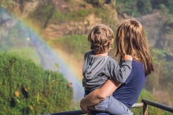 Mom and son on the background of Majestic landscape of Elephant waterfall in summer at Lam Dong Province, Dalat, Vietnam. Look at the rainbow.