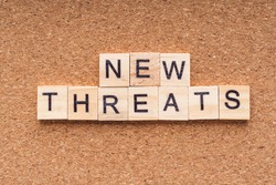 NEW THREATS word written on wood block. NEW THREATS text on wooden table. Business  Covid- 19 Concept
