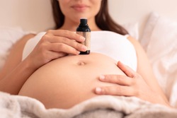 A pregnant woman using essential oil for health and skin beauty. Relaxation remedy. 