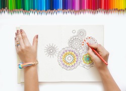 The girl draws with colored pencils. White background.