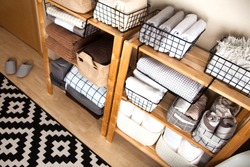 Spring cleaning of closet. Vertical tidying up storage. Neatly folded bed sheets in the metal black baskets for wardrobe. Nordic style.