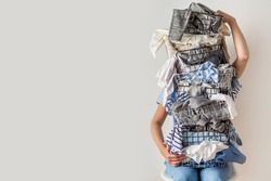 Surprised woman holding metal laundry basket with messy clothes on white background. Laundry. Isolated housewife. Copy space. Textile. Dirty wardrobe. Decluttering concept. Disorganized wife.