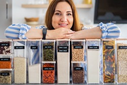 Happy woman professional space organizer smiling posing with plastic case boxes for comfortable product storage. Cute female enjoying healthy food organization, placing and sorting and kitchen