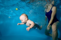 Toddler swims with his mother underwater in the pool. Close-up. Portrait. Horizontal orientation