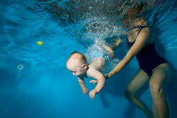 Mom teaches and trains the happy baby to swim underwater in the pool. Close-up. Portrait. Horizontal orientation.