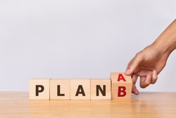 Hand flip wooden cube with the word PLAN A to PLAN B on white background. Business concept