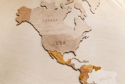 Wooden map of the world on a light background. Self made. Plywood. In beige tones. North and Latin America. Geography. USA, Canada, Alaska, Mexico, Brazil, Cuba, Venezuela.
