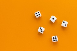 Gaming dice on orange background. Playing cube with numbers. Items for board games. Flat lay, top view with copy space.