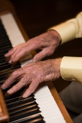 Old man plays piano so fast his fingers are blurred.