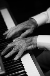 Old man plays piano with withered hands. Hands in motion leave motion trail as he plays quickly.