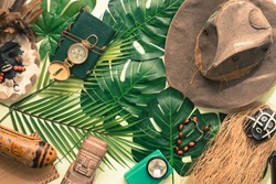 Travel concept around the world. Masks, compass, Indiana Jones style hat, Tropical leaves 