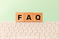 The word FAQ Frequently asked questions, used on the Internet, in online stores or offices, answering standard queries, Inscription on wooden blocks against the background of a computer keyboard