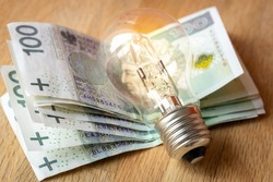 Polish money Several hundred Polish zlotys and a light bulb, the concept of increasing energy and electricity prices in Poland