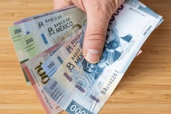 Mexico money held in hand, various pesos banknotes