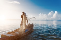 Shot of water spatter from fisherman while throwing fishing net on the lake. Fisherman with fishing net in the morning light sunshine. Stop motion of water drop.