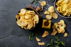 Bowl of home made potato chips served with mustard, rosemary, fleur de sel salt on stone background. Top view. Copy space