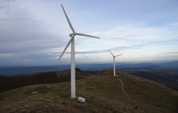 Wind power generator on a peak in Stara Planina, Bulgaria, in autumn evening, with clouds and antennas.