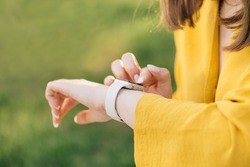Smart watch on woman's hand outdoor. Girl using smartwatches. Young woman browsing notificatins on modern smart wristwatches connected to internet. Female using touchscreen on gadget.