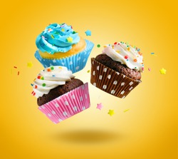 Cupcakes flying over yellow background. Colorful festive cupcakes for party, birthday.