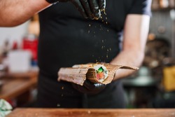 Close-up of professional chef's hands in black gloves making sushi and rolls in a restaurant kitchen. Japanese traditional food. Preparation process.