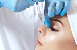 The doctor cosmetologist makes prick in the nose to correct the hump of a beautiful woman in a beauty salon. Cosmetology skin care.