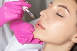 Woman with beautiful clean skin. Cosmetologist does injections for lips augmentation and anti wrinkle of a beautiful woman. Women's cosmetology in the beauty salon.