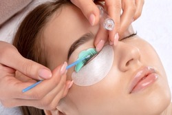 Make-up artist makes the procedure of lamination and dyeing of eyelashes to a beautiful woman in a beauty salon. Eyelash extensions. Eyelashes close-up
