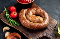 
grilled spiral sausage with spices on a cutting board on a stone background