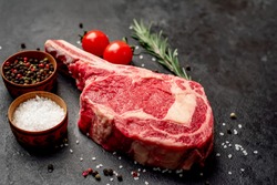 
Raw cowboy steak with spices on stone background