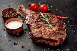 grilled cowboy steak with spices on a knife on a stone background