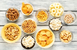 Unhealthy food. pretzels, various chips, croutons, cookies in bowls. unhealthy food for figure, heart, skin, teeth. An assortment of fast carbohydrates. On a wooden background