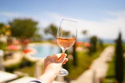 Female hand with glass of r wine. Cozy hotel on the coast of Lagos. Sea view, beautiful landscape in Portugal Adventure in Europe (travel photo).