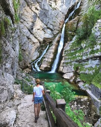 Girl on hiking, back to camera. Alpine waterfall Savica in the nation park Triglav, Slovenia