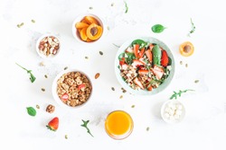 Breakfast with muesli, strawberry salad, fresh fruit, orange juice, nuts on white background. Healthy food concept. Flat lay, top view