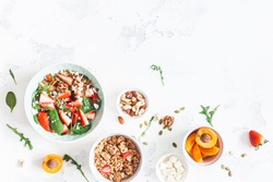 Breakfast with muesli, strawberry salad, fresh fruit, nuts on white background. Healthy food concept. Flat lay, top view.