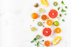Fruit background. Colorful fresh fruit on white table. Orange, tangerine, lime, kiwi, grapefruit. Flat lay, top view, copy space.
