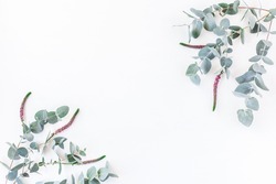 Flowers composition. Frame made of pink flowers and eucalyptus branches on white background. Flat lay, top view, copy space