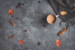 Autumn composition. Cup of coffee, blanket, autumn leaves, cinnamon sticks on black background. Flat lay, top view.
