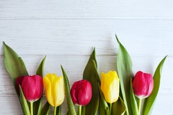 Wooden white background and red and yellow tulips. Conception holiday, March 8, Mother's Day.