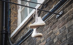 A pair of shoes dangling outside a brick wall at Brick Lane market in London