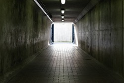 Thames Barrier passageway in London, a dim and concrete corridor leading to bright exit