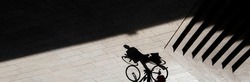 Abstract background shadow silhouette of a person climbing a bike next to outdoor stairs, high contrast sepia black and white