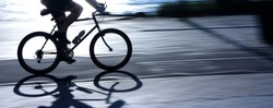 Blurry cyclist silhouette and shadow on a  bike path  in sunset, panning shot
